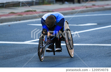 Child Racing in a Wheelchair on the City Street During a Sunny Day 120954078