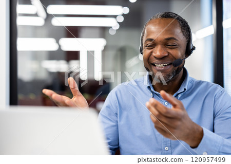 Smiling African American businessman wearing headset gestures during online meeting. Professional environment with focus on business communication. Mature man, confident, engaged, technology friendly Smiling African American businessman wearing headset gestures during online meeting. Professional environment with focus on business communication. Mature man, confident, engaged, technology friendly 120957499