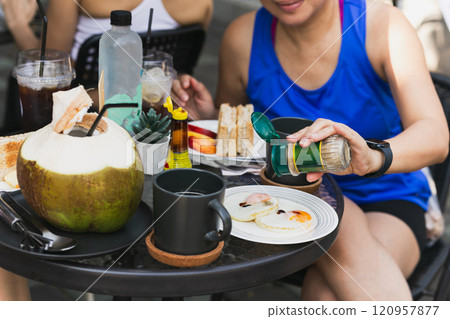 Female friend having breakfast with  fried eggs and coffee on table. 120957877