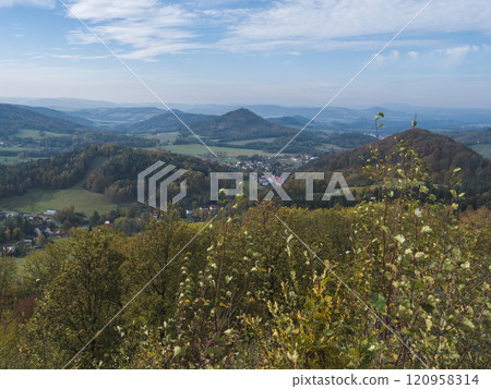 Panoramic view from viewpoint Stredni vrch near Dolni Prysk, Ceska Kamenice. Autumn landscape with colorful forest, hills and blue cloudy sky in Luzicke hory Lusatian Mountains, Czech Republic. 120958314