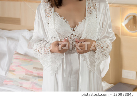A woman wearing white lace robe over a nightgown. A woman wearing white lace robe over a nightgown. 120958843
