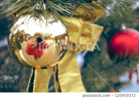 a golden toy on the Christmas tree in which a photographer with a camera is reflected. High quality photo a golden toy on the Christmas tree in which a photographer with a camera is reflected. High quality photo 120959372