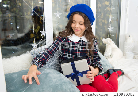 Best christmas gifts. Child excited about unpacking her gift. Kid little girl in beret hat hold box with bow at home window background. Opening christmas gift. Small cute girl received holiday gift Best christmas gifts. Child excited about unpacking her gift. Kid little girl in beret hat hold box with bow at home window background. Opening christmas gift. Small cute girl received holiday gift 120959392