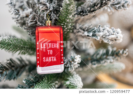 A close-up of a letters to santa text toy on a Christmas tree with lights on background 120959477