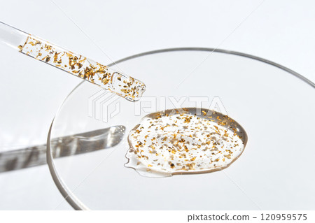 Golden particles in transparent serum on glass surface with dropper 120959575