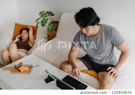 Couple lover, man working at home while woman is having a phone call. Couple lover, man working at home while woman is having a phone call. 120959634