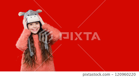 Winter fashion style. Teenager knitted fashion. Outdoor lifestyle fashion. Teenager girl in a winter warm hat isolated on red. Happy girl in winter hat. Signature look 120960220