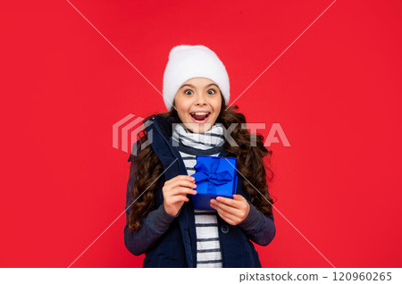 happy amazed child in puffer jacket and hat hold box. kid with present. teen girl happy amazed child in puffer jacket and hat hold box. kid with present. teen girl 120960265