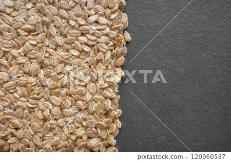 Close up photo of organic spelt flakes on a dark slate background, selective focus. 120960587