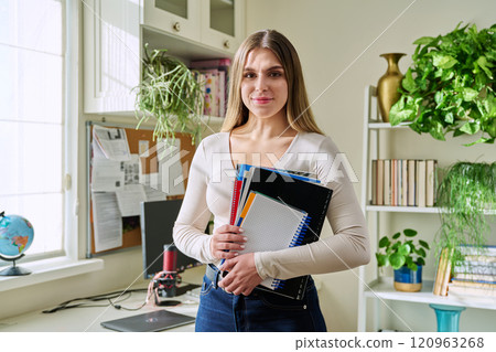 Portrait of woman university student holding textbooks notebooks, in home 120963268