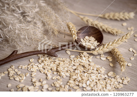 Wooden spoon holds oats, grains, wheat stalks on wooden surface, natural food, healthy recipes concept Wooden spoon holds oats, grains, wheat stalks on wooden surface, natural food, healthy recipes concept 120963277