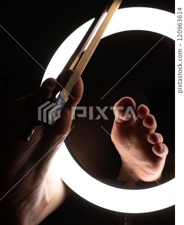 female legs with a violin bow in close-up in a round lamp. the concept of playing the violin .foot fetishism 120963614