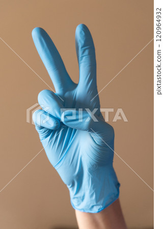 A person who is wearing a bright blue glove is making a wellrecognized peace A person who is wearing a bright blue glove is making a wellrecognized peace 120964932
