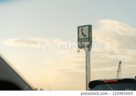 Emergency telephone sign on the highway and sunset 120965664
