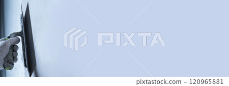 Worker uses a trowel to apply microcement on a wall for repair. Banner for your text. 120965881