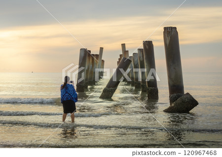 A beautiful sunrise at old leaning cement pillars Cha-Am beach, Phetchaburi, Thailand. 120967468