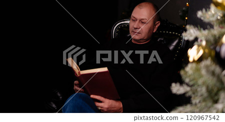serene moment unfolds as a man reads intently in his living room chair, with the twinkling lights of the Christmas tree illuminating the space.Copy space serene moment unfolds as a man reads intently in his living room chair, with the twinkling lights of the Christmas tree illuminating the space.Copy space 120967542