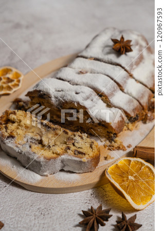 Slices of Christmas Stollen in Christmas lights and decoration. Traditional sweet fruit loaf with icing sugar festive pastry dessert. Holiday baking food 120967593