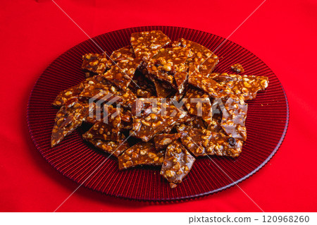 Homemade sweet gozinak with various nuts on a red plate, Christmas concept 120968260