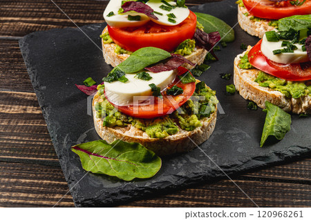 Rice cakes with mozzarella, avocado, spinach, onion on a stone on a wooden table Rice cakes with mozzarella, avocado, spinach, onion on a stone on a wooden table 120968261