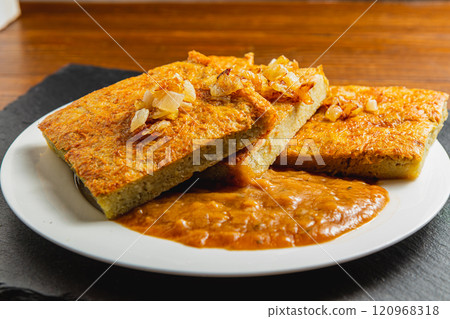 Oven-baked potato pancakes with mushroom sauce and onions on a stone board Oven-baked potato pancakes with mushroom sauce and onions on a stone board 120968318