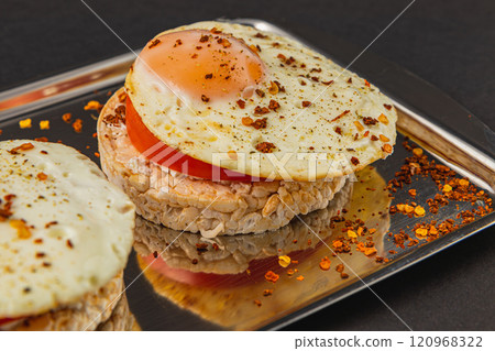 Sandwiches with egg on rice bread with tomato on a plate on a black background Sandwiches with egg on rice bread with tomato on a plate on a black background 120968322