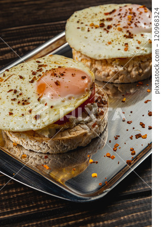Freshly fried egg on rice bread with tomato and feta cheese on a metal tray 120968324