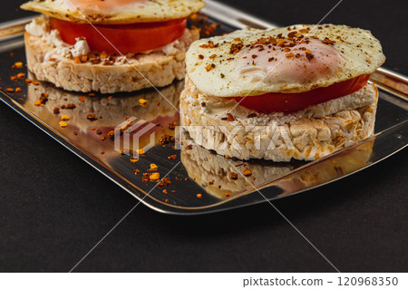 Freshly fried egg on rice bread with tomato and feta cheese on a metal tray 120968350