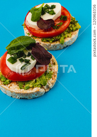 Rice cakes with mozzarella avocado spinach onion on a blue background Rice cakes with mozzarella avocado spinach onion on a blue background 120968356