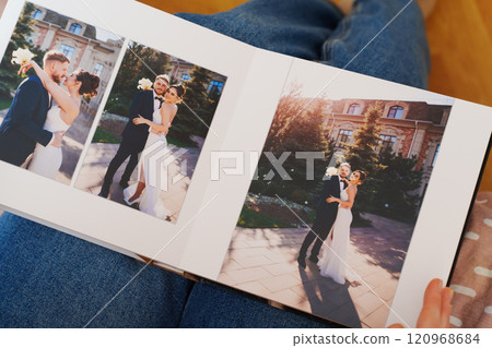 Female hands flipping through a photo book with wedding photos 120968684