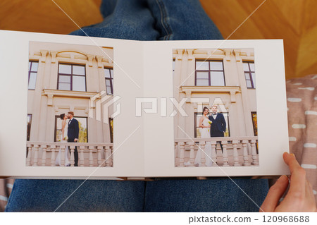Female hands flipping through a photo book with wedding photos 120968688