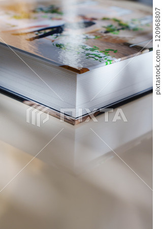 Corner of closed thick photo book with plastic pages and photo cover.  120968807