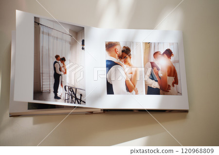 an open photo book with wedding photos on a white table 120968809