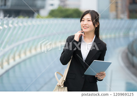穿著西裝、在辦公區拿著平板電腦的女商人 穿著西裝、在辦公區拿著平板電腦的女商人 120969125