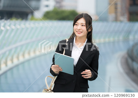 穿著西裝、在辦公區拿著平板電腦的女商人 穿著西裝、在辦公區拿著平板電腦的女商人 120969130