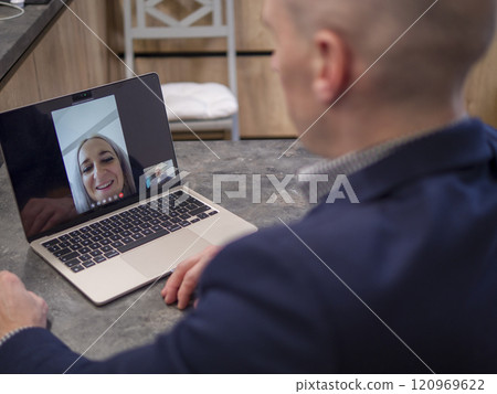 Utilizing technology for efficient communication and collaboration in a modern business setting: business professional using laptop for remote video conference with colleagues from home office 120969622