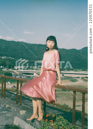 Barefoot woman in pink dress poses with a view on an abandoned rooftop Barefoot woman in pink dress poses with a view on an abandoned rooftop 120970531