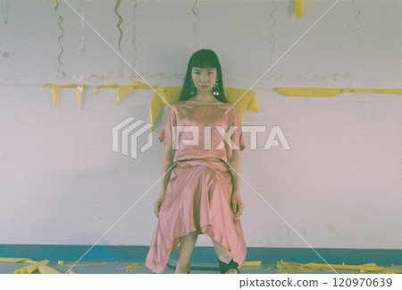 一位身穿粉紅色洋裝、長髮的女人坐在椅子上看著鏡頭 120970639
