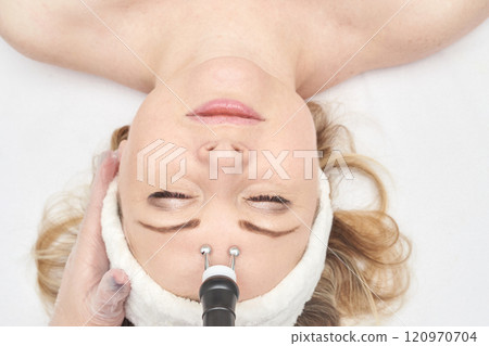 Female caucasian adult receiving facial microcurrent treatment in spa setting Female caucasian adult receiving facial microcurrent treatment in spa setting 120970704