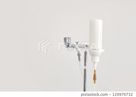 Airbrush makeup system with white bottle and metal components on stand 120970732