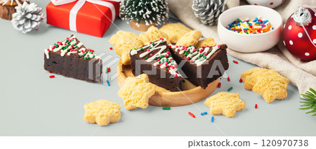 Chocolate brownies and cookies in wooden tray with christmas decoration on pastel green table Chocolate brownies and cookies in wooden tray with christmas decoration on pastel green table 120970738