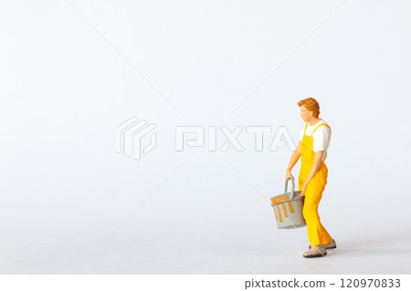 Miniature figure of a painter dressed in yellow overalls on white background 120970833