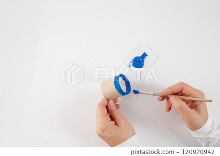 cardboard tube in one hand and the paintbrush in the other. a palette with blue paint, a crafting or DIY activity, creative use of everyday materials like a cardboard tube and paint cardboard tube in one hand and the paintbrush in the other. a palette with blue paint, a crafting or DIY activity, creative use of everyday materials like a cardboard tube and paint 120970942