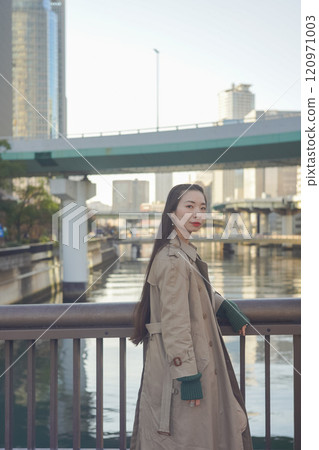 日落時，一位外國女子靠在海岸線鐵軌上的柵欄上 120971003
