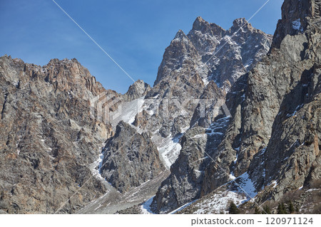 rugged mountain peak under blue sky, jagged edges, snow, high-altitude location rugged mountain peak under blue sky, jagged edges, snow, high-altitude location 120971124