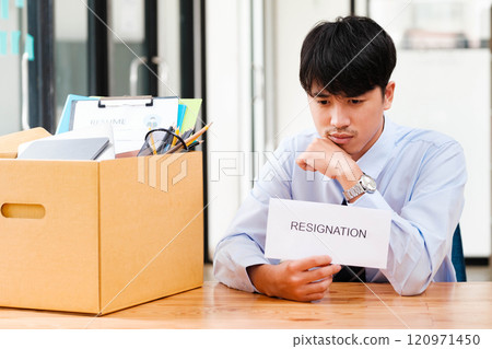 Disappointed Businessman Holding Resignation Letter and Packing Belongings. Disappointed Businessman Holding Resignation Letter and Packing Belongings. 120971450