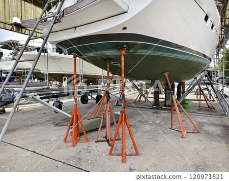 A boat is carefully lifted under a covered structure 120971821
