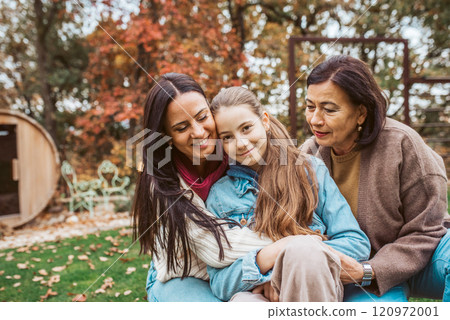 Mature daughter, grandmother and granddaugter sitting in the garden. Mother's day and multigenerational family concept. 120972001