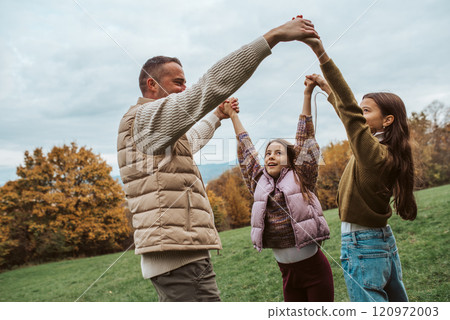 Father dancing with daughters, holding hands. Father dancing with daughters, holding hands. 120972003