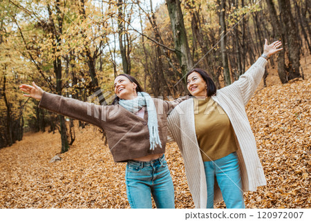 Mature daughter and her older mom standing in the middle of fores with open arms. Mother's day concept. Mature daughter and her older mom standing in the middle of fores with open arms. Mother's day concept. 120972007